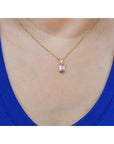 14k gold necklace with a pink genuine sapphire pendant worn by a person in a blue top.