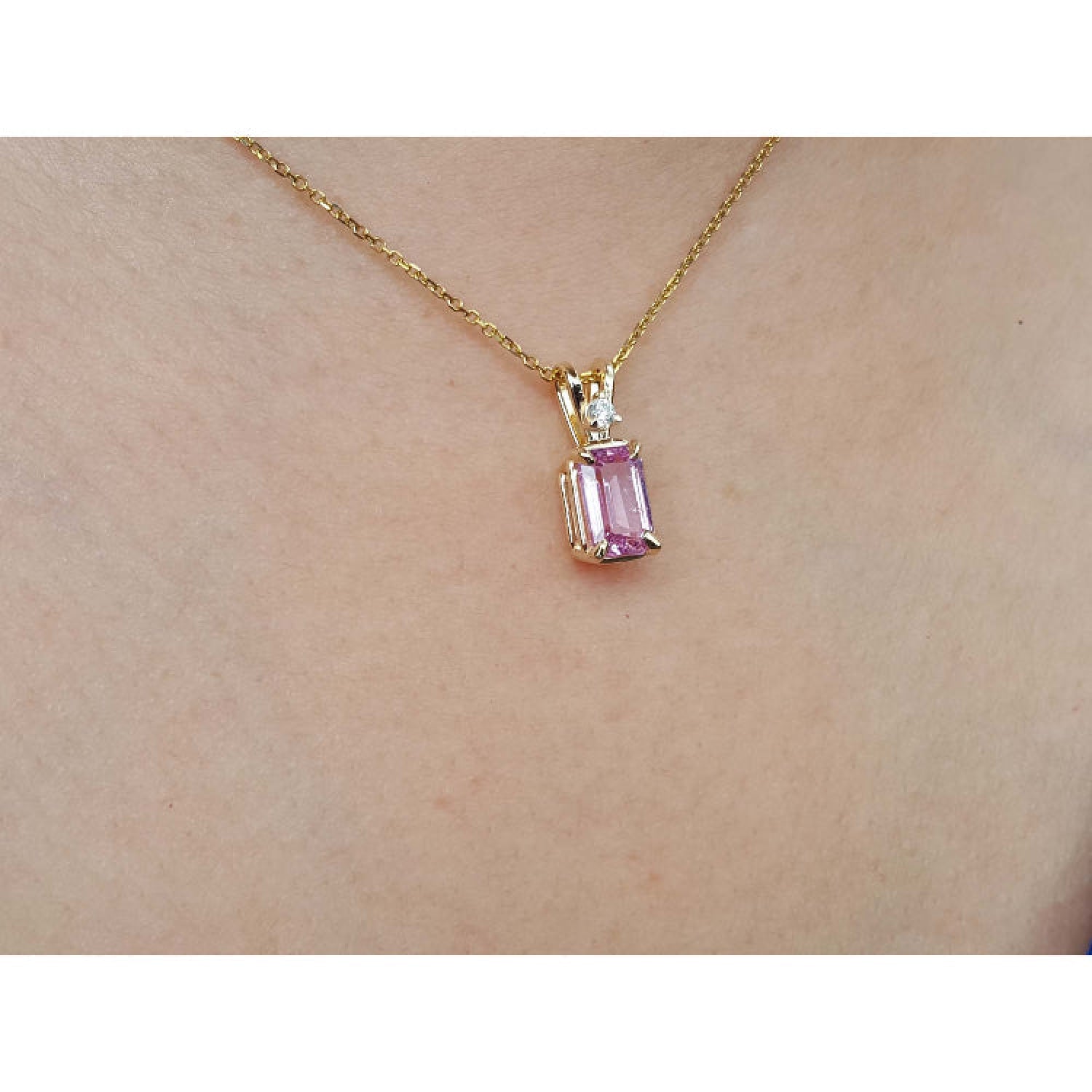 14k solid gold necklace with a natural pink sapphire pendant on a person's neck.