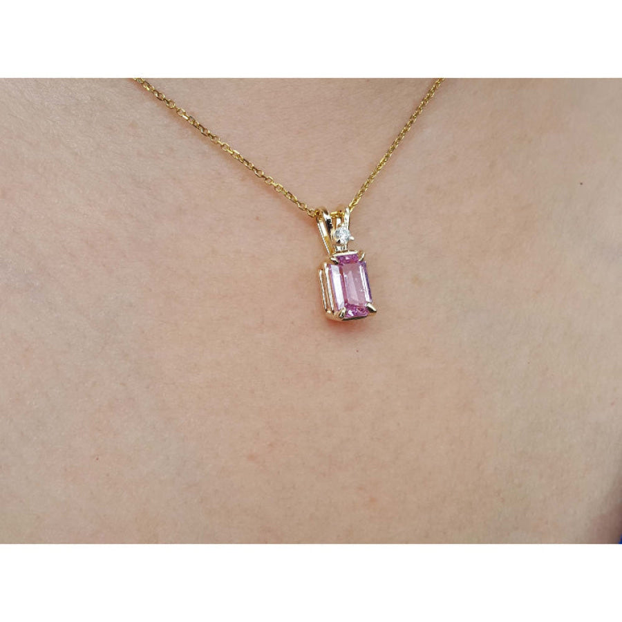14k solid gold necklace with a natural pink sapphire pendant on a person's neck.