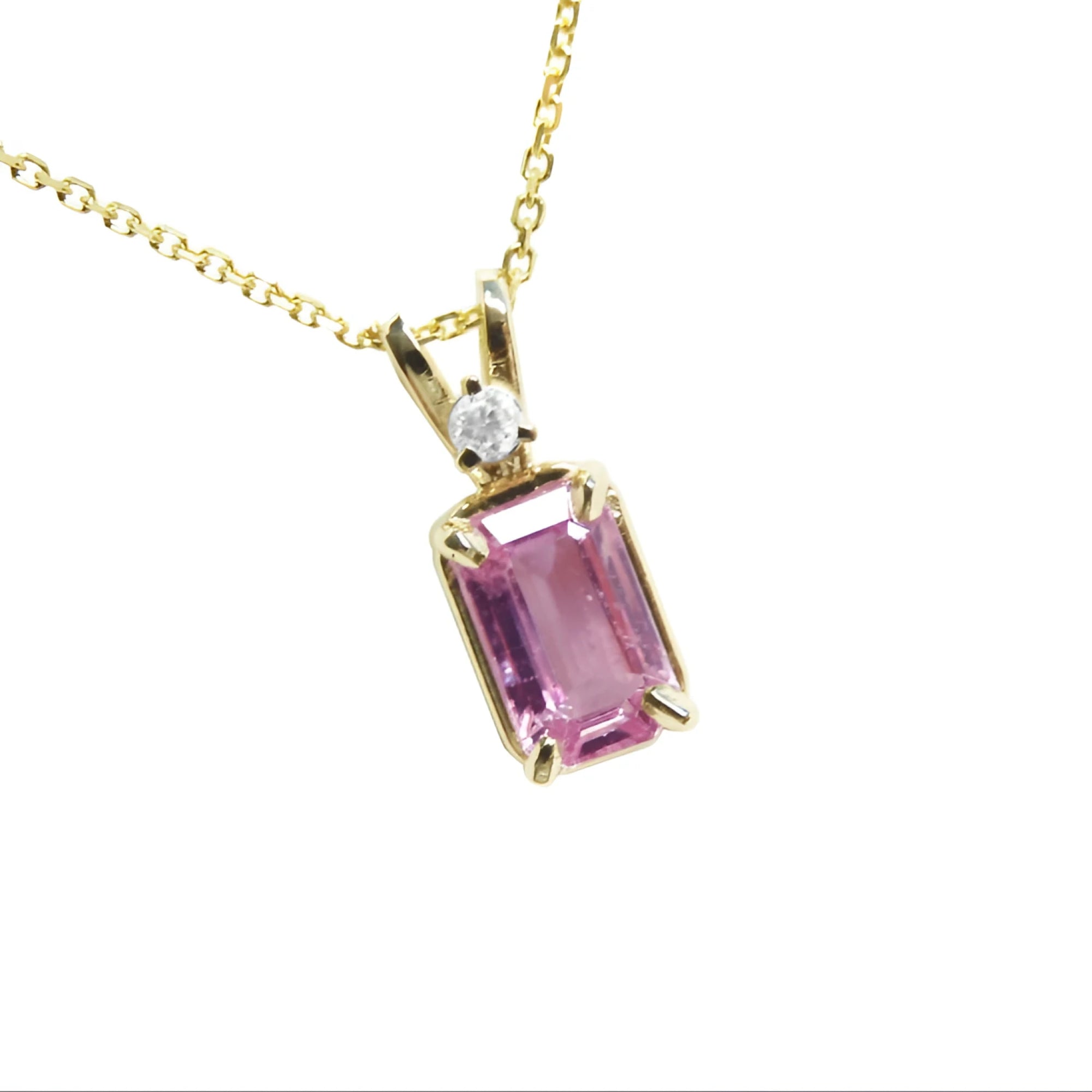 A natural emerald-cut pink sapphire and diamond pendant necklace in a prong setting, crafted in 14k yellow gold.