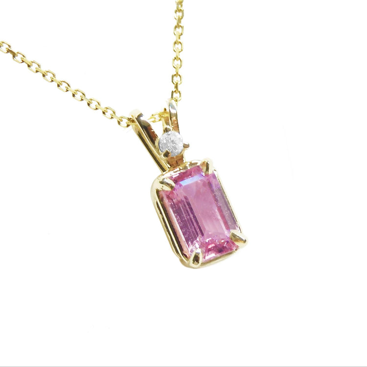 Emerald-cut pink sapphire pendant necklace, with a natural diamond in a prong setting, crafted in 14k yellow gold.