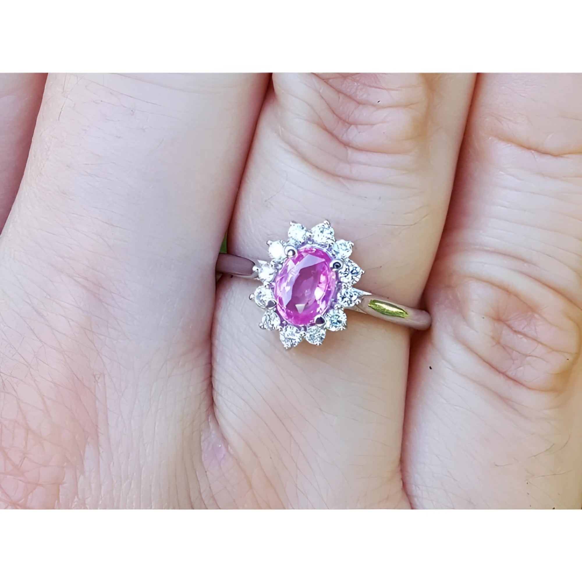 Natural pink sapphire ring for women halo diamond in 14k white gold, on a finger.