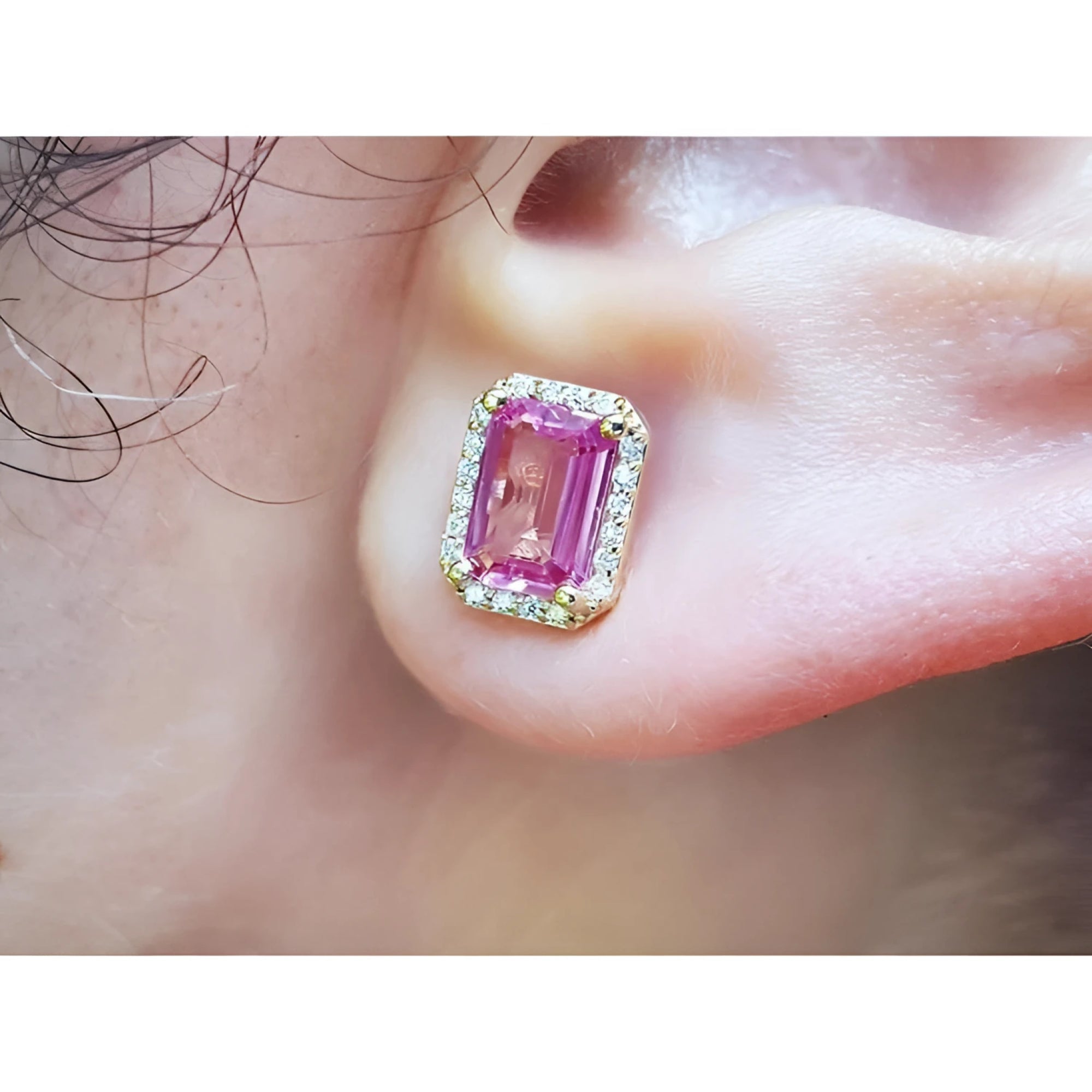 Natural pink sapphire stud earrings halo diamonds 14k yellow gold, worn on an ear.
