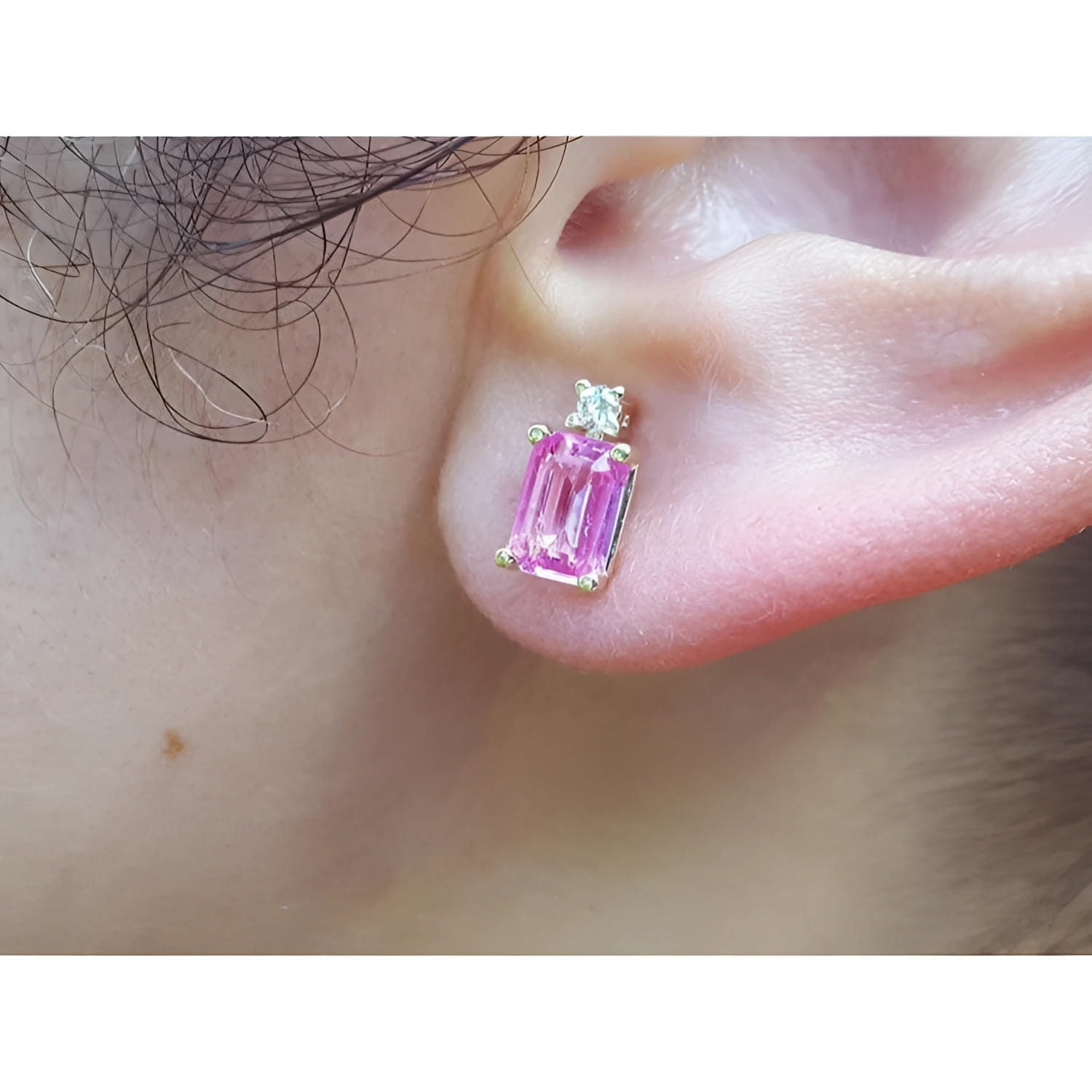 1.51 carat rectangular pink sapphire stud earrings with natural diamonds in 14K yellow gold on an ear.