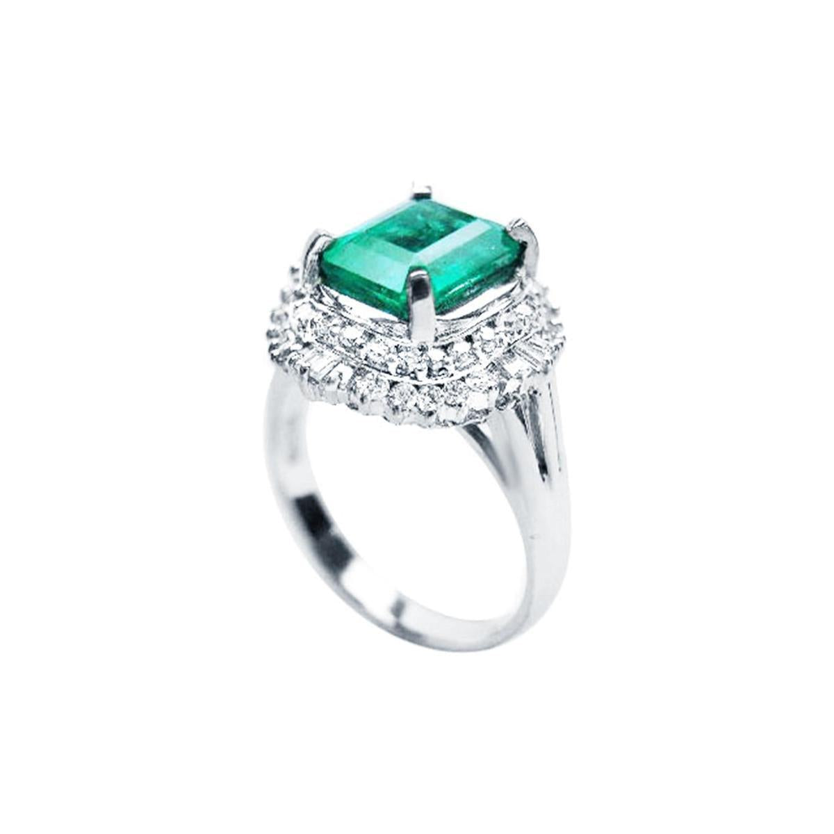 A platinum emerald ring on top and side profile view.