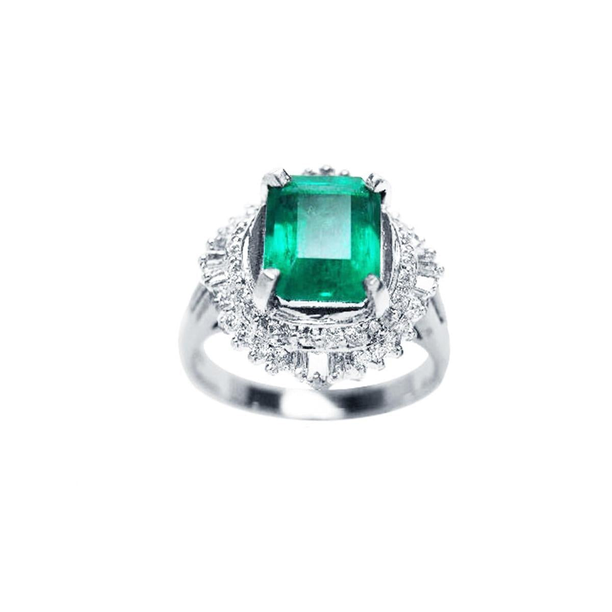 A platinum ring with a colombian emerald and diamond accents on a topside view.