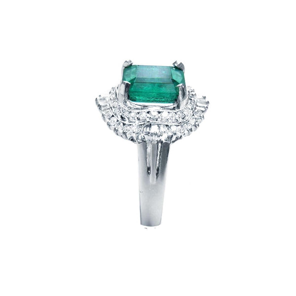 Ring with a colombian emerald and diamond-studded band on a white background.