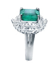 Ring with a colombian emerald and diamond-studded band on a white background.