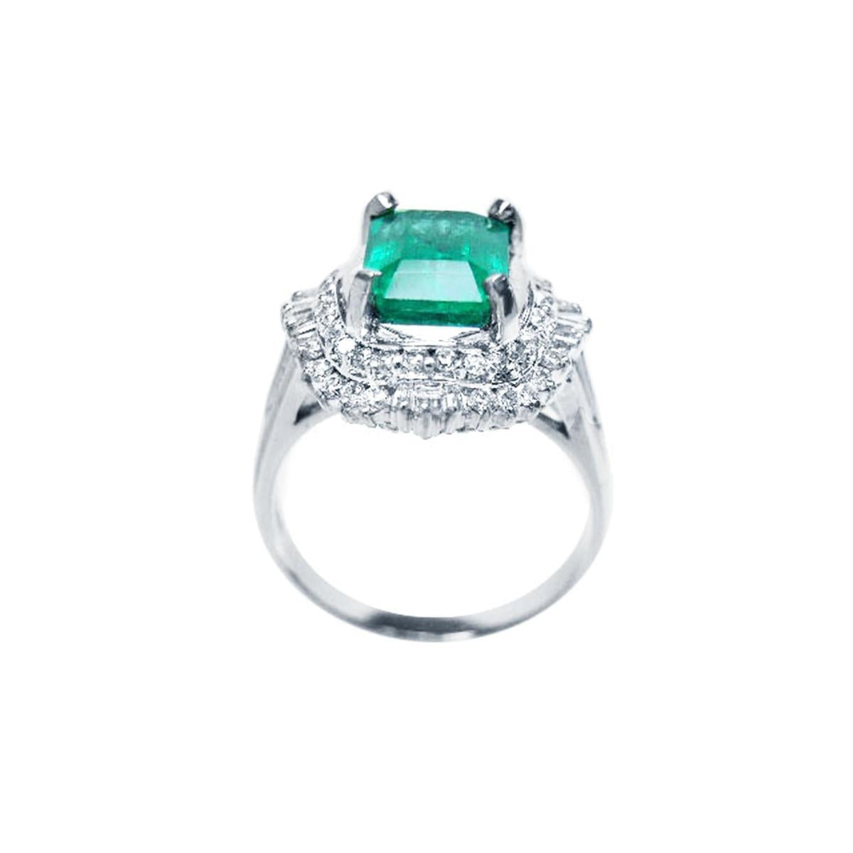 Ring with a colombian emerald and diamond accents on a white background.