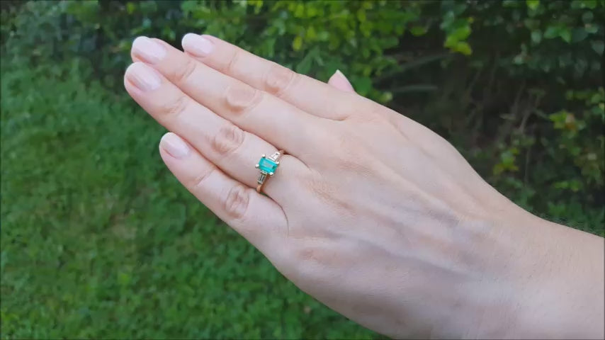 Gold ring with emerald and side baguette diamonds.