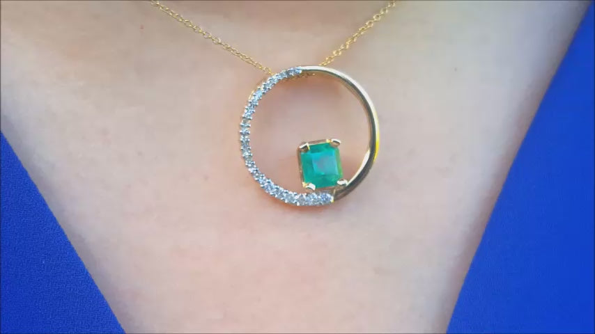 A woman dressing a blue top with a circle of life gold pendant necklace.