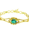 Gold bracelet with a Muzo mine natural emerald oval cut on a white background.