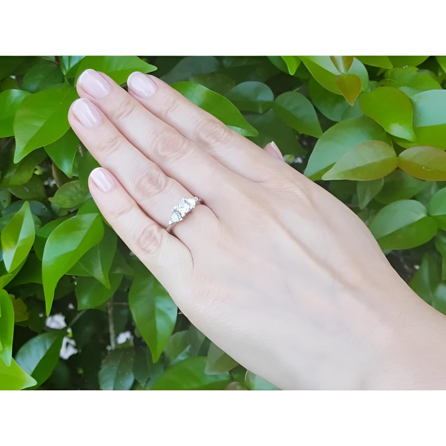 14K white gold ring with a princess cut diamond center and two trillion side diamonds on a hand.