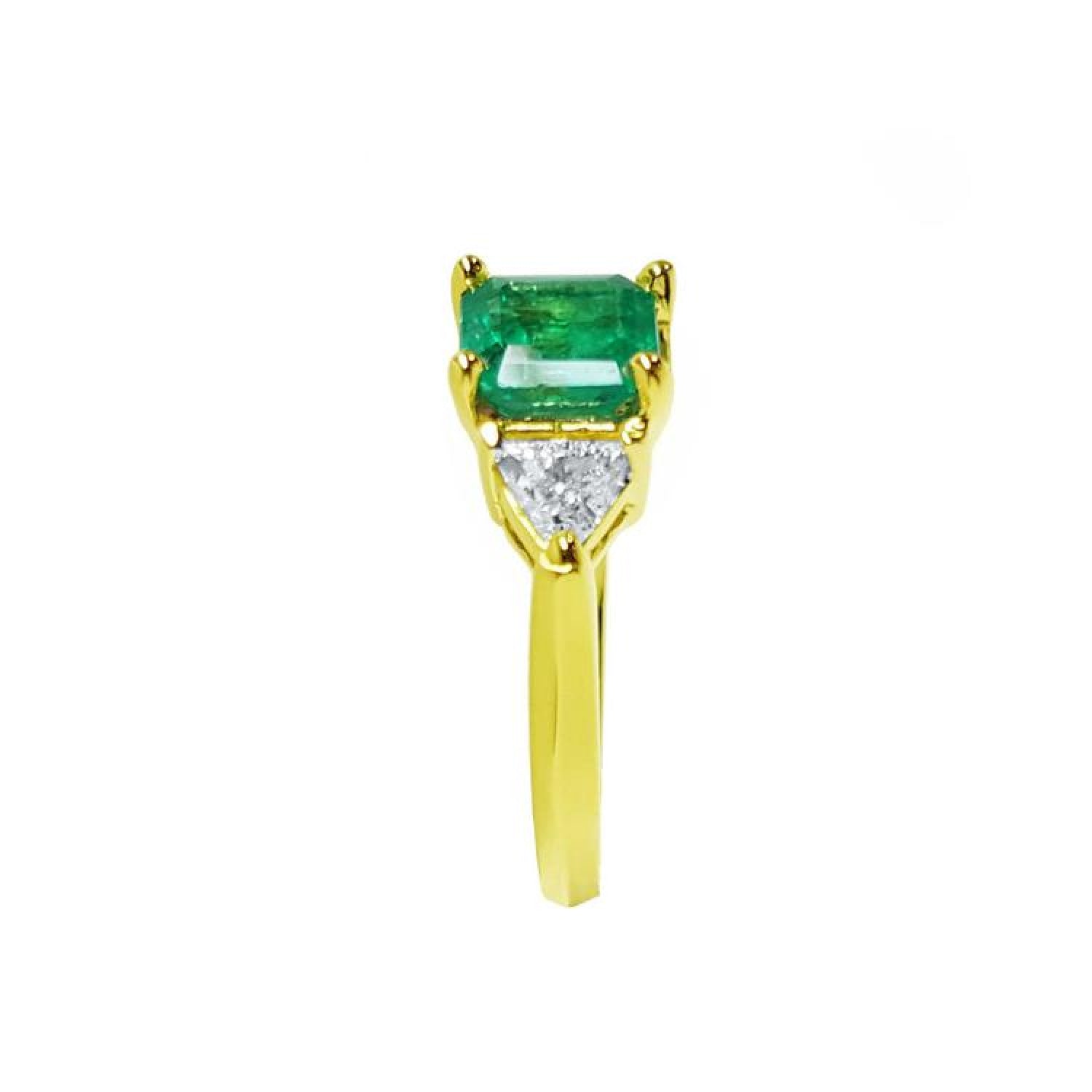 18K yellow gold three-stone ring with a rectangular Colombian emerald flanked by two trillion-cut diamonds.