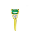 Yellow gold 18k ring for women with a natural colombian emerald and trillion side diamonds.