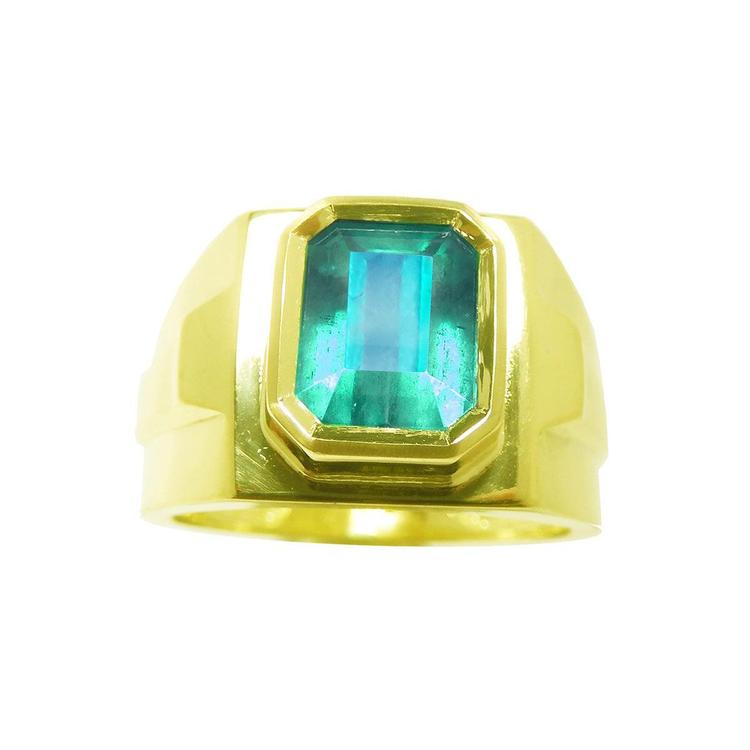 Topside view of a yellow gold emerald ring for men with bezel setting.