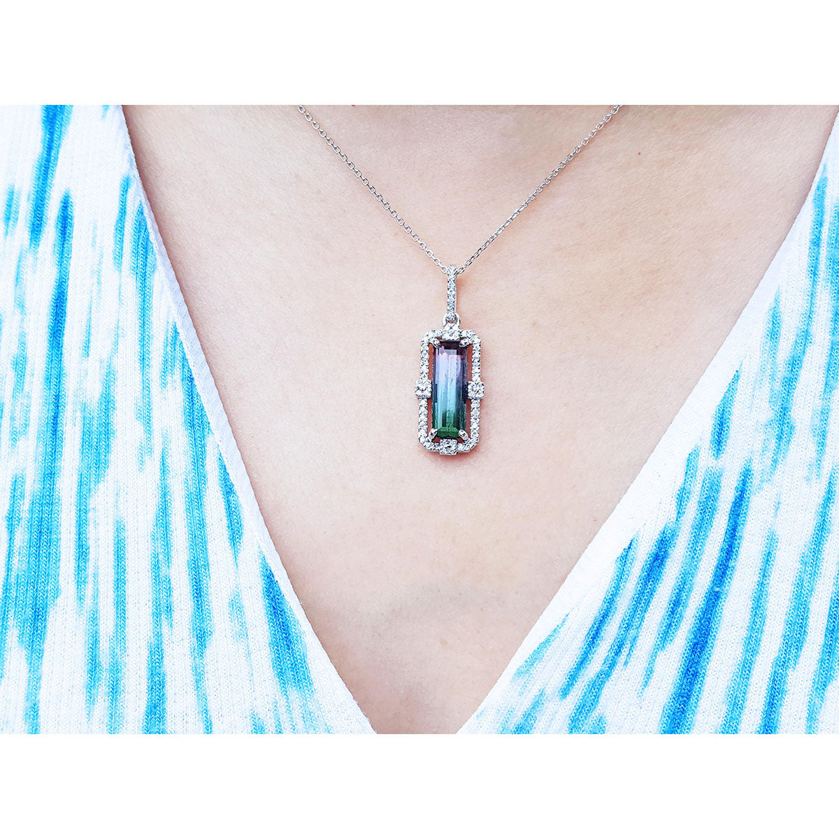 bicolor tourmaline gemstone necklace on a person wearing a blue and white patterned top.