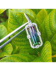 Jewelry pendant with a bicolor tourmaline gemstone on a green leaf background.