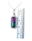 Watermelon tourmaline pendant on a chain with a ruler for scale on a white background.