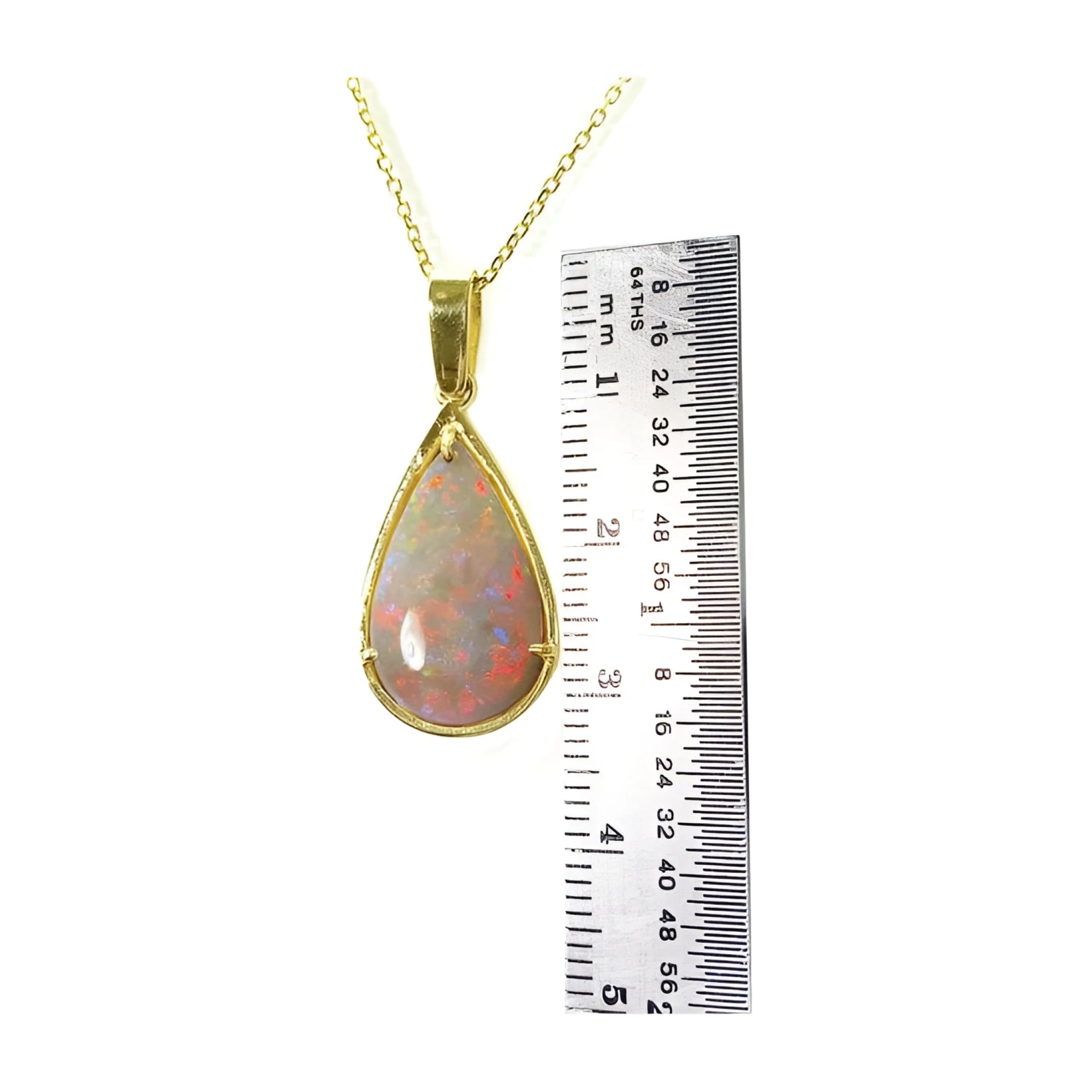 Pear-shaped Australian opal pendant with red/orange fire, set in 14k yellow gold, next to a ruler.