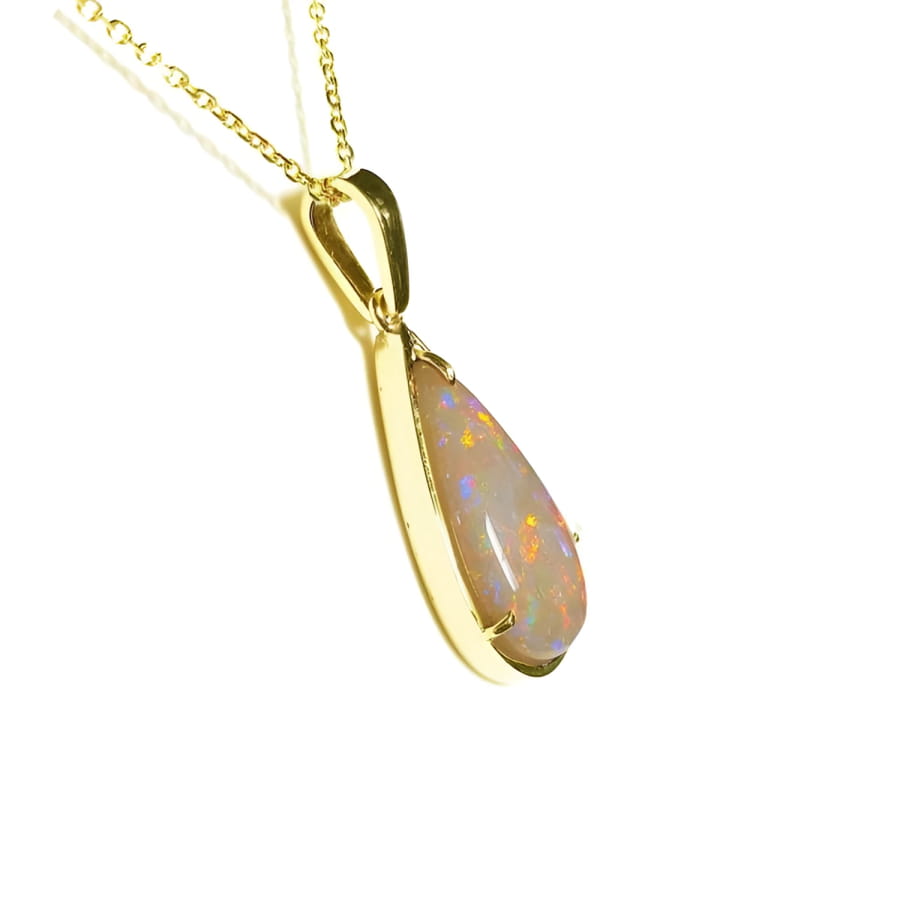 Pear-shaped Australian opal pendant with fiery red/orange hues in 14k yellow gold setting on a chain.