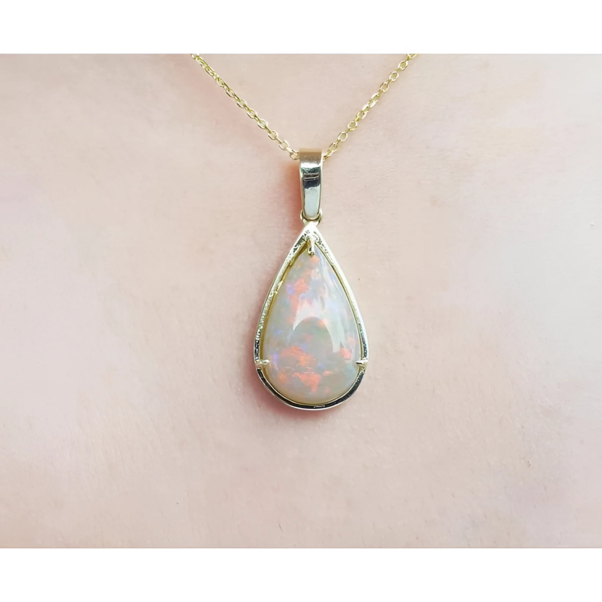 Pear-shaped Australian opal pendant with fiery red-orange hues in 14k yellow gold.