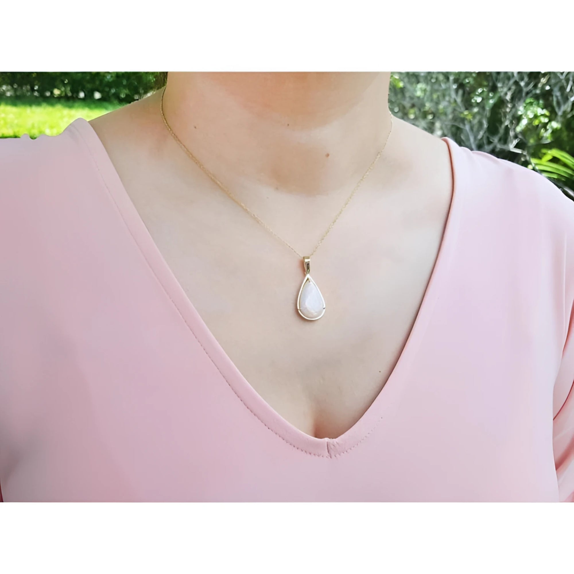 Pear-shaped Australian opal pendant with fiery red-orange hues in 14k yellow gold, worn on a woman.
