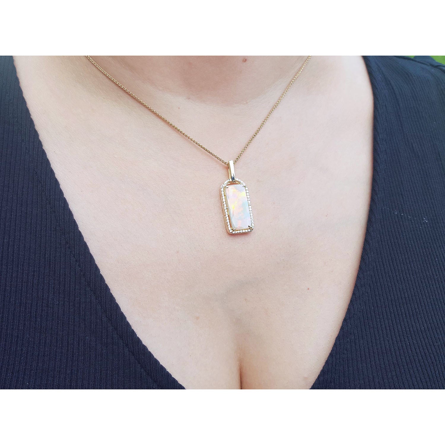 Necklace with a natural opal pendant worn by a person against a white background
