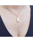 Necklace with a natural opal pendant worn by a person against a white background