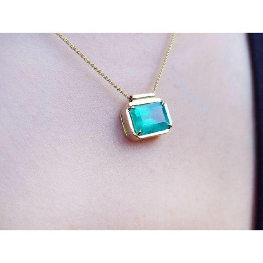 18K yellow gold necklace with a vibrant deep green emerald solitaire in an east-west setting.