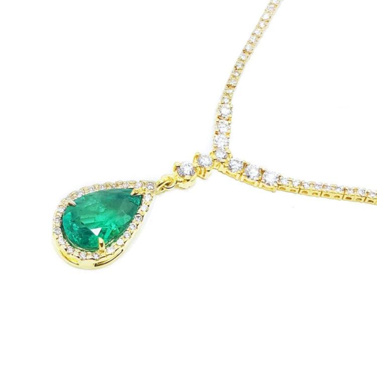 Right side of a real emerald necklace pear cut natural crafted in 18k yellow gold, encircled by a halo diamond