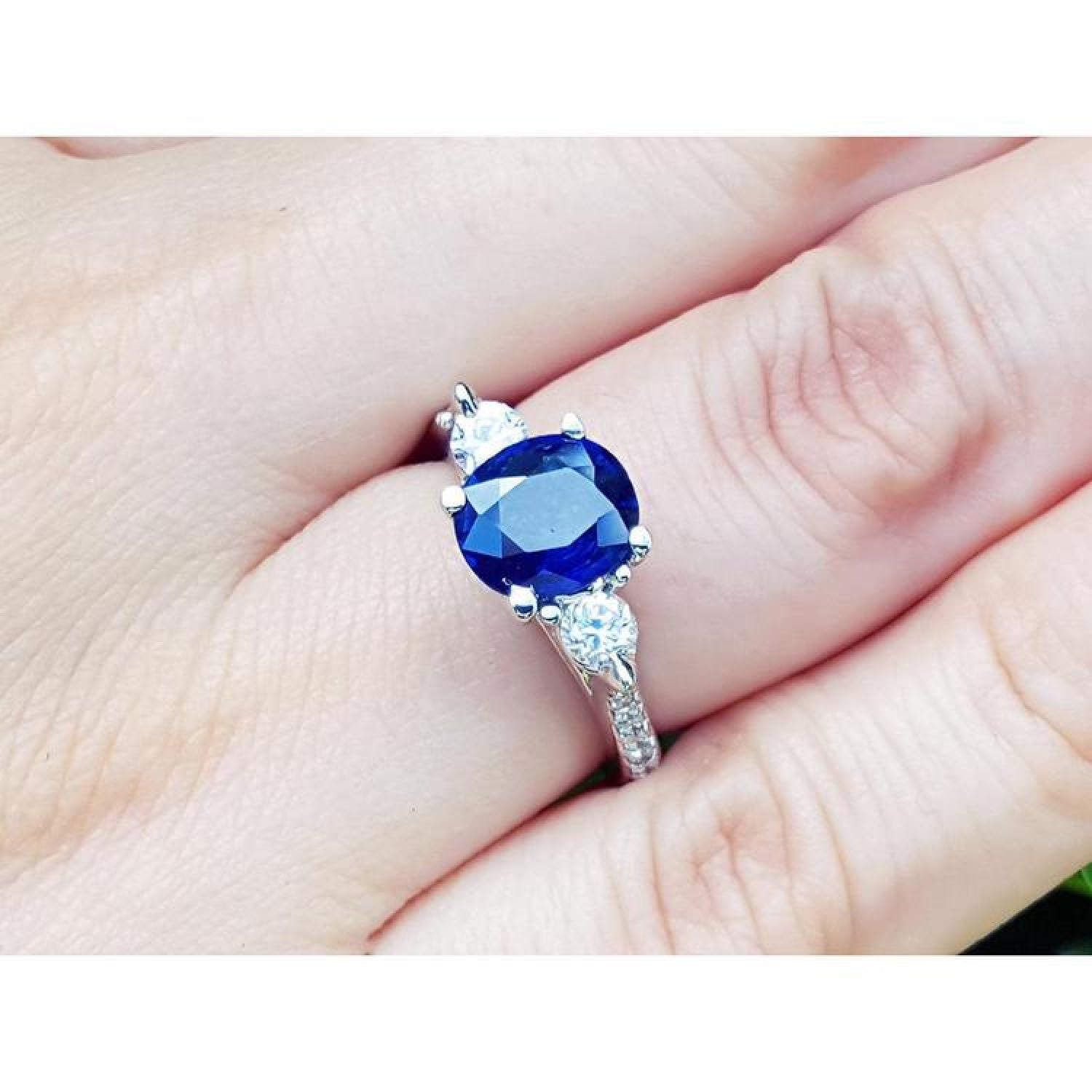 Women's 14K white gold ring with a deep blue oval sapphire and two round side diamonds.