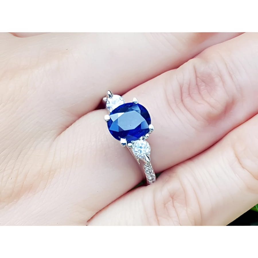 Women's 14K white gold ring with a deep blue oval sapphire and two round side diamonds.