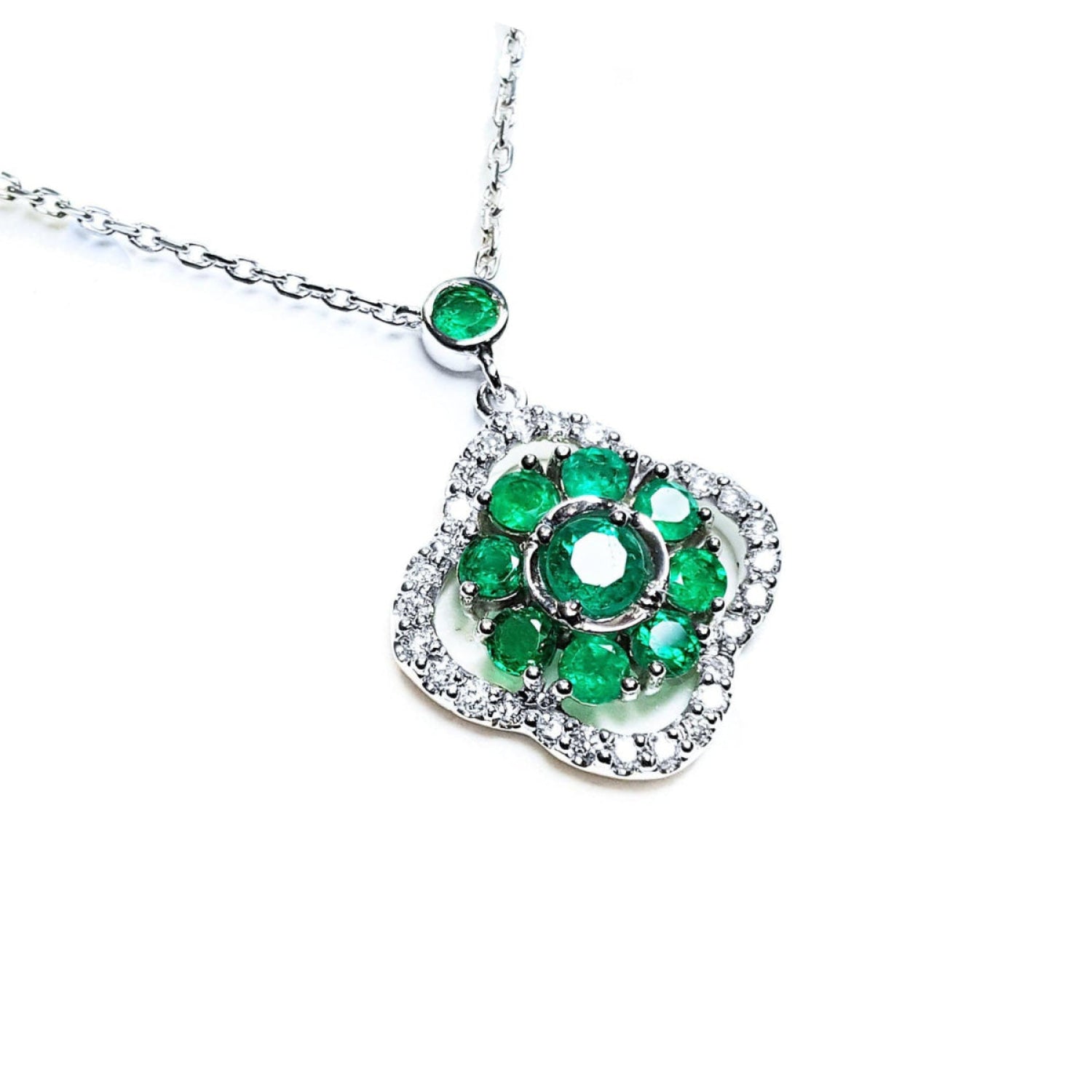 A natural emeralds necklace cluster set within a delicate 4-leaf clover design, crafted in 14k white gold and diamonds.