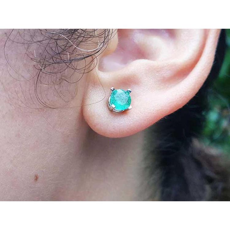 An ear wearing a Colombian emerald stud earring made of 14k white gold and push backs.