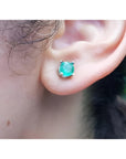 An ear wearing a Colombian emerald stud earring made of 14k white gold and push backs.