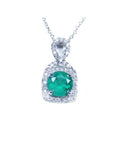 Round deep bluish-green emerald and diamond halo pendant in 18K white gold.