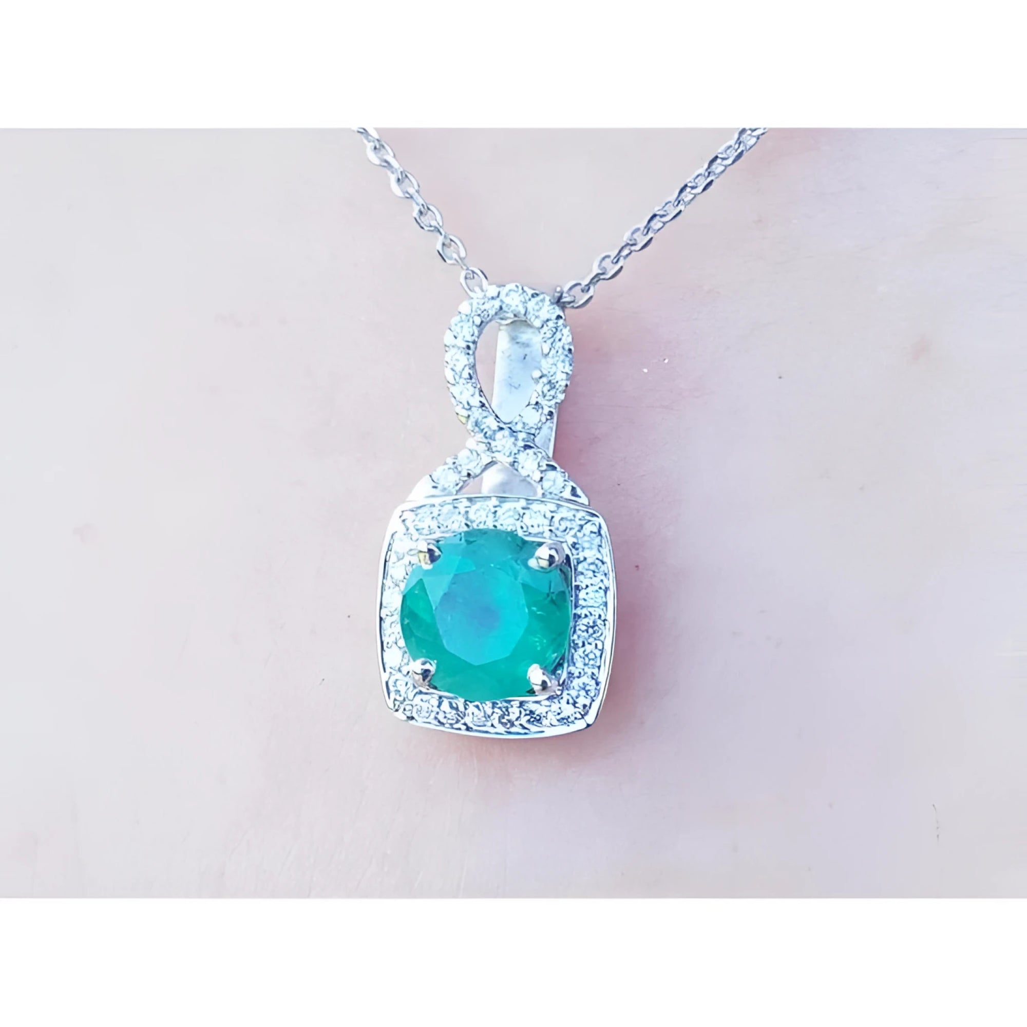 1.08 ct. round emerald and diamond pendant in 18K white gold, featuring a deep bluish-green emerald.
