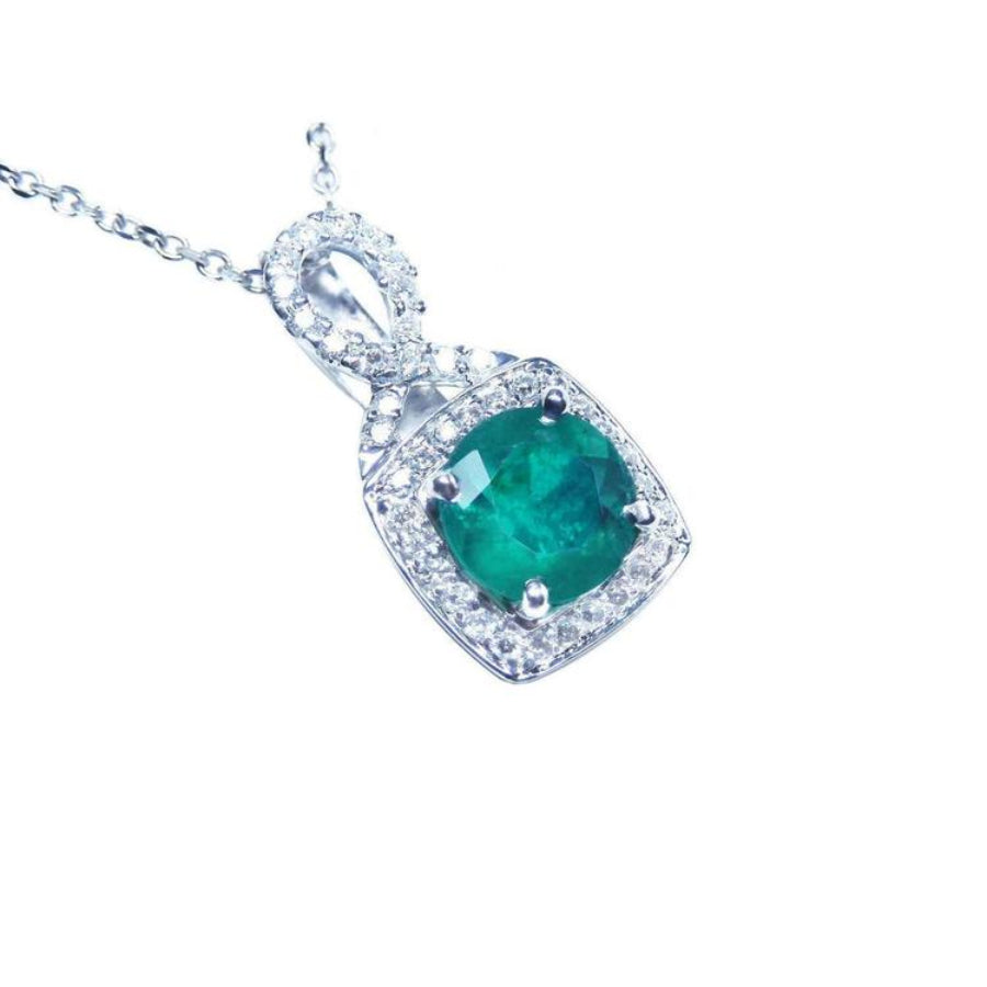 Round cut emerald pendant with natural halo diamond accents made of 18k white gold.