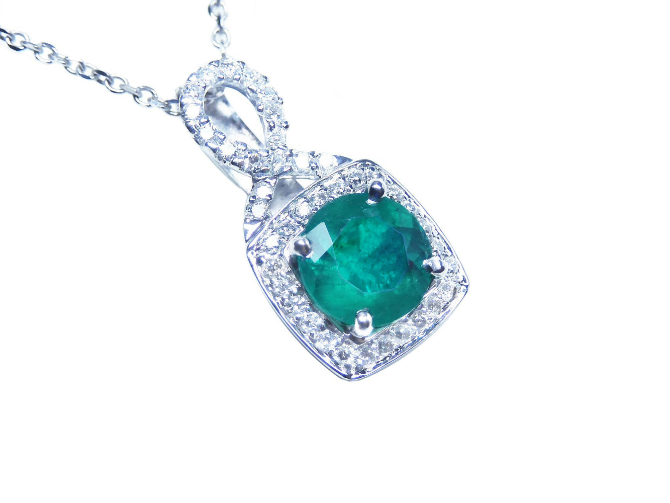 Emerald pendant with diamond accents on a right position topside view.