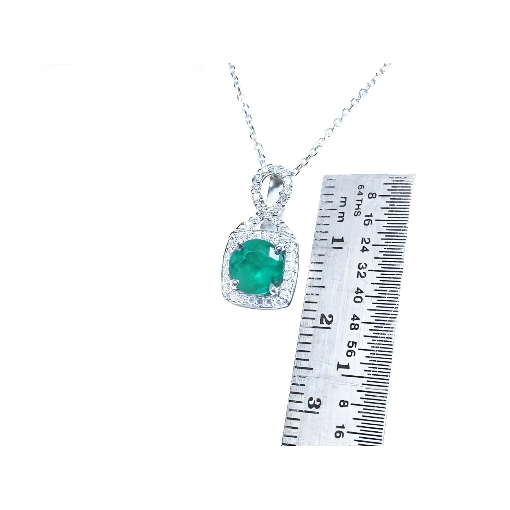 1.08 ct round deep bluish-green emerald and diamond halo pendant in 18K white gold, shown with a ruler.