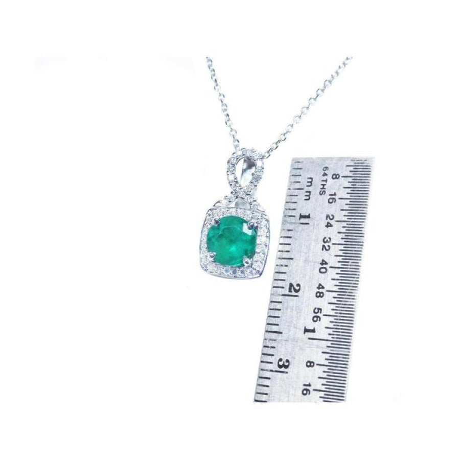 1.08 ct round deep bluish-green emerald and diamond halo pendant in 18K white gold, shown with a ruler.