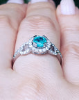 A white gold emerald ring on a person's finger.