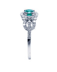 Showcasing the top emerald setting, gallery, and band of a round cut emerald ring in white gold.