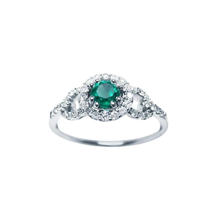 This women's ring features a Colombian emerald with a round cut, surrounded by a halo of natural diamonds.