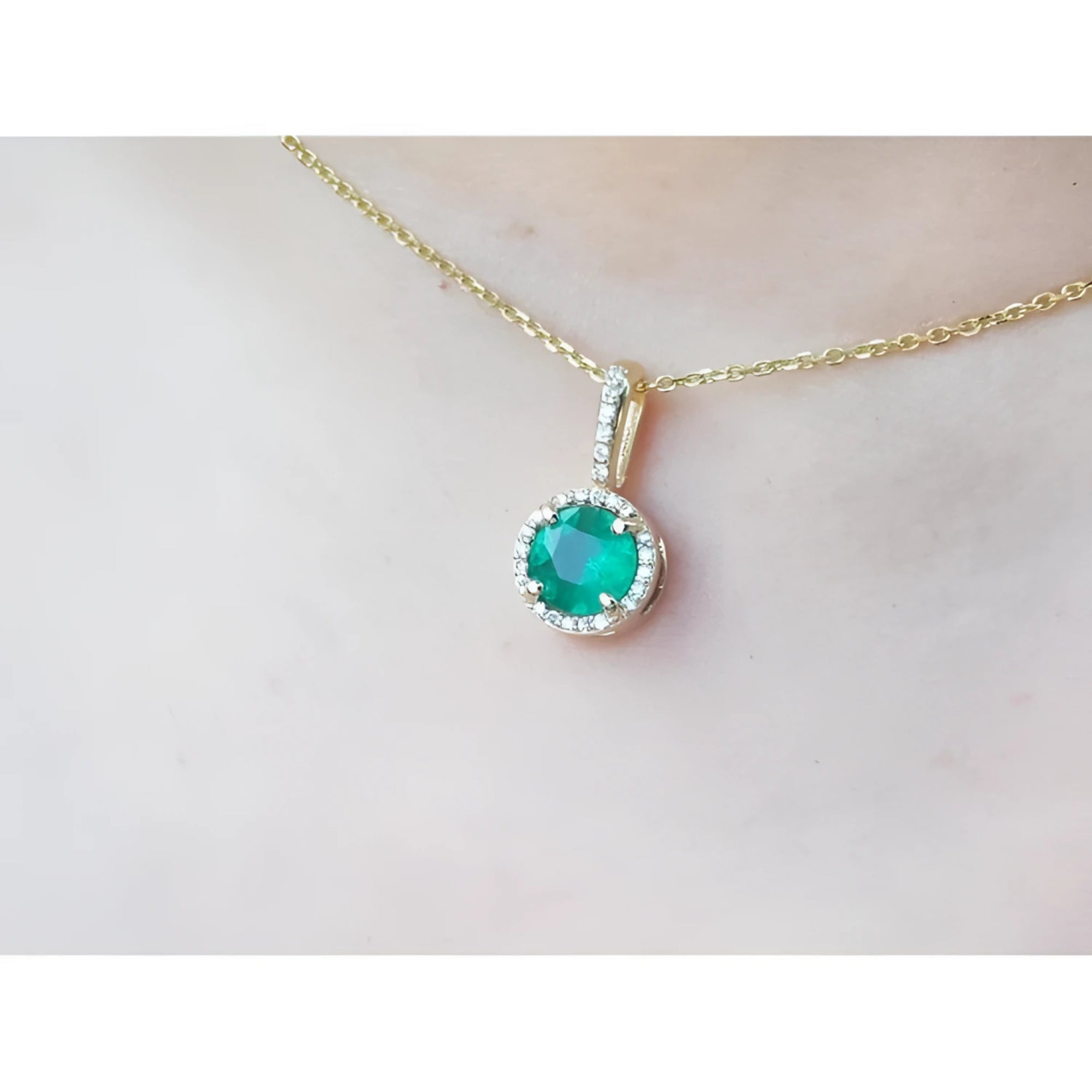 Round cut Colombian emerald pendant with halo diamonds on a 14K gold chain.
