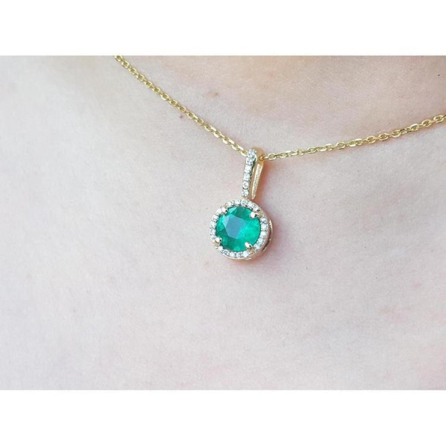Round cut Colombian emerald pendant with halo diamonds on a 14K gold chain.
