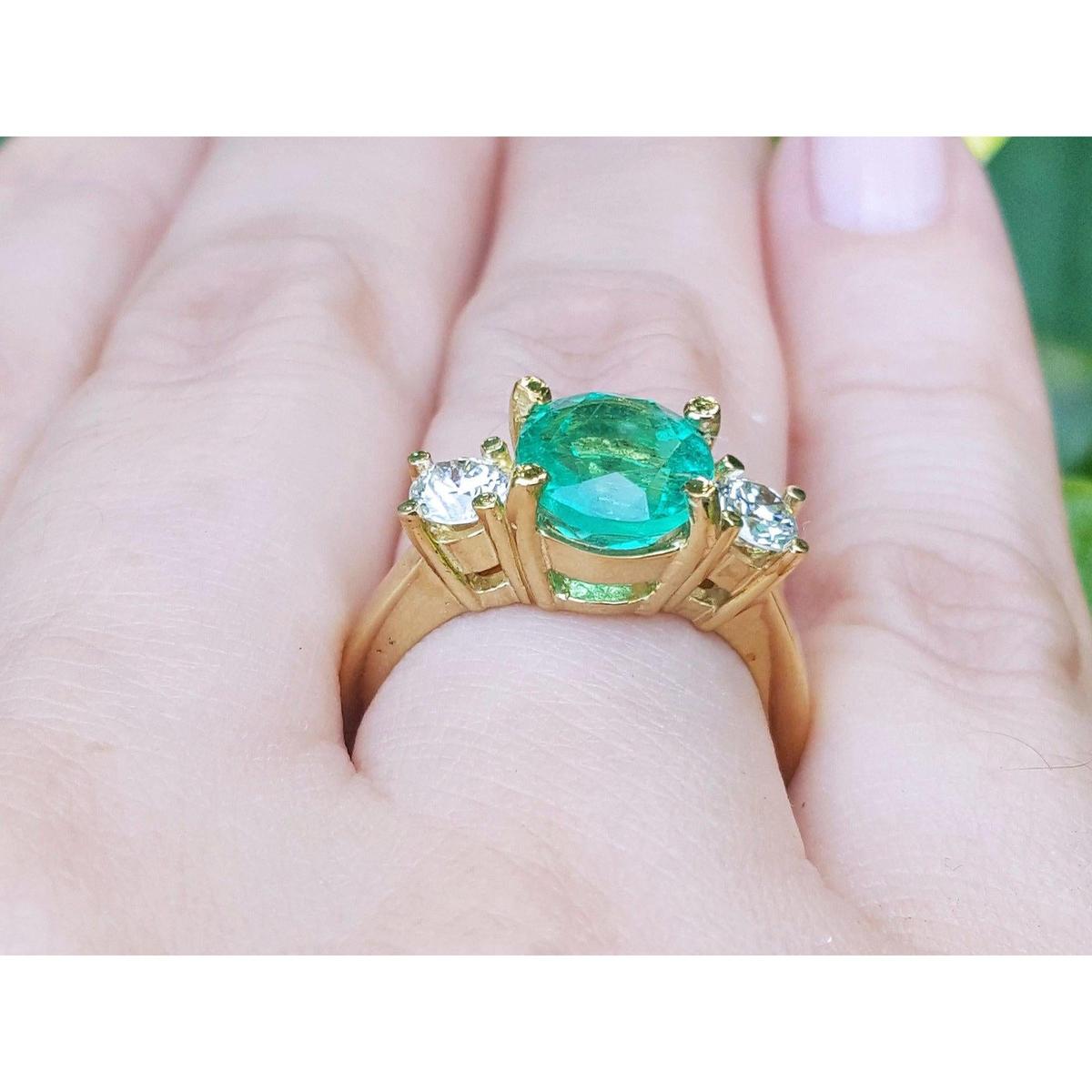 Underside profile view of a 18k yellow gold emerald ring on a hand.