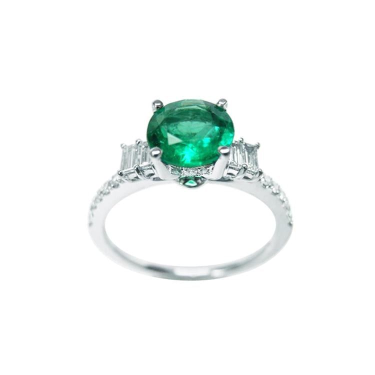 1.10 ct. round Colombian emerald ring with baguette side diamonds on a 14K white gold band.
