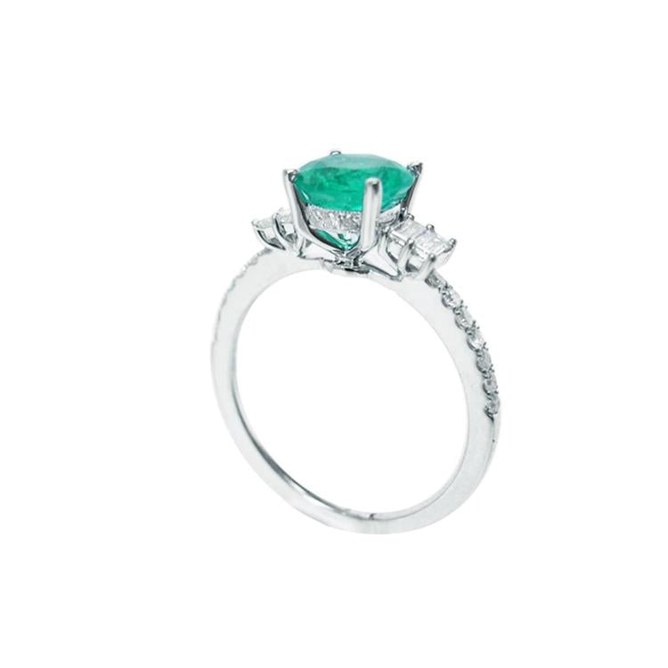 1.10 ct. round Colombian emerald ring with baguette side diamonds on a 14K white gold band.